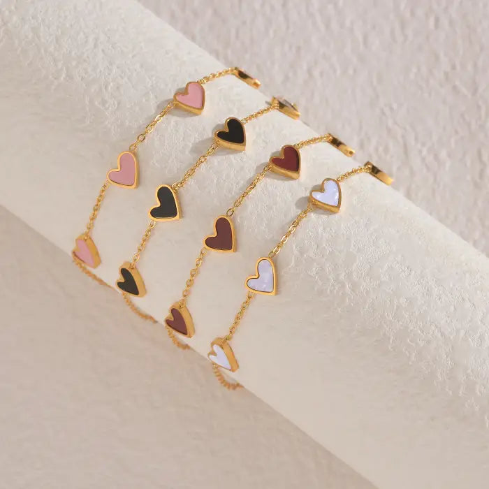 heart-charm-bracelet set showing pink, black, brown, and white heart designs on gold chains, highlighting a trendy multi-color collection