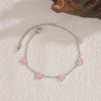 heart-charm-bracelet with pink enamel hearts on silver chain displayed on soft surface, creating a cute delicate style ideal for gifting
