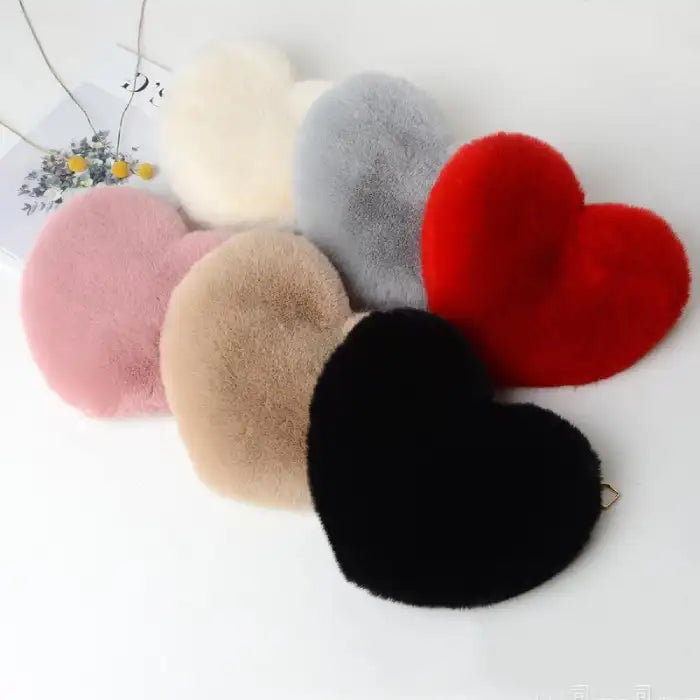 Heart shoulder bag collection shown in multiple plush colors in a flat lay arrangement.