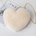 Cream-colored plush heart shoulder bag with gold chain on a minimal white setup.