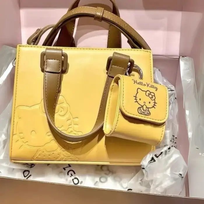 Yellow Hello Kitty handbag in original box featuring embossed design and brown straps for gifting.