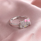Hello kitty silver ring with pink bow and crystal face from jewelry set on pink satin background.