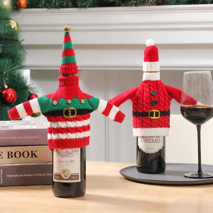 Decorative Christmas wine bottle sweaters with striped elf and cable knit Santa patterns displayed near Christmas tree