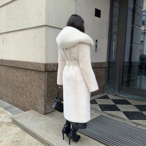 Back view of hooded long plush coat in white styled with black heels and bag.