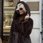 Hooded long plush coat in belted black paired with black boots and sunglasses for bold winter style.