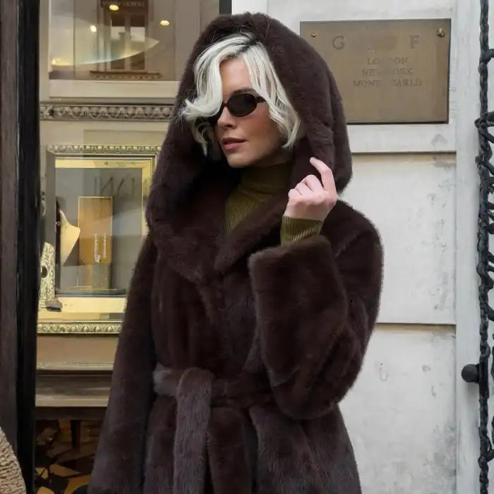 Hooded long plush coat in belted black paired with black boots and sunglasses for bold winter style.