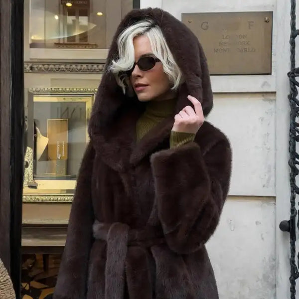 Hooded long plush coat in belted black paired with black boots and sunglasses for bold winter style.