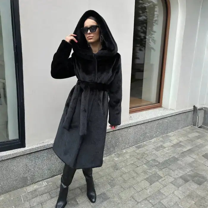 Hooded long plush coat in dark brown with belt and sunglasses for chic cold-weather street style.