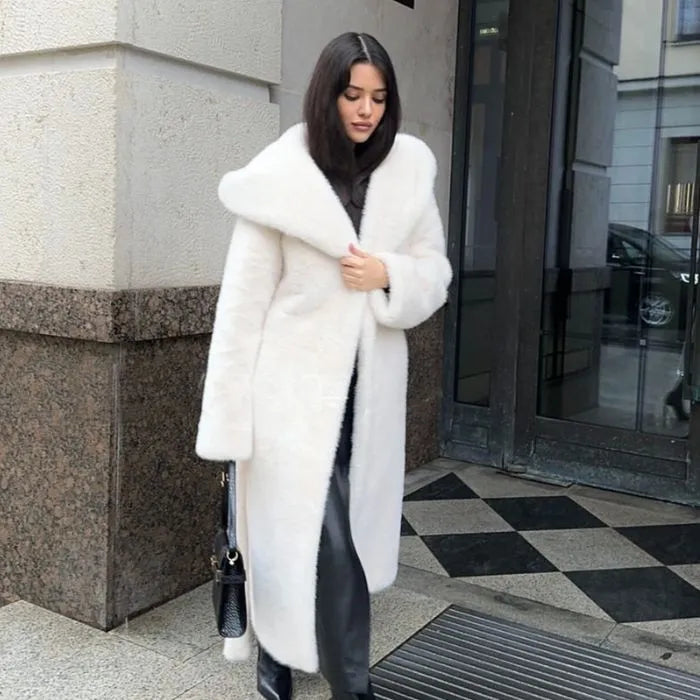 Hooded long plush coat in white styled elegantly with black boots and bag.