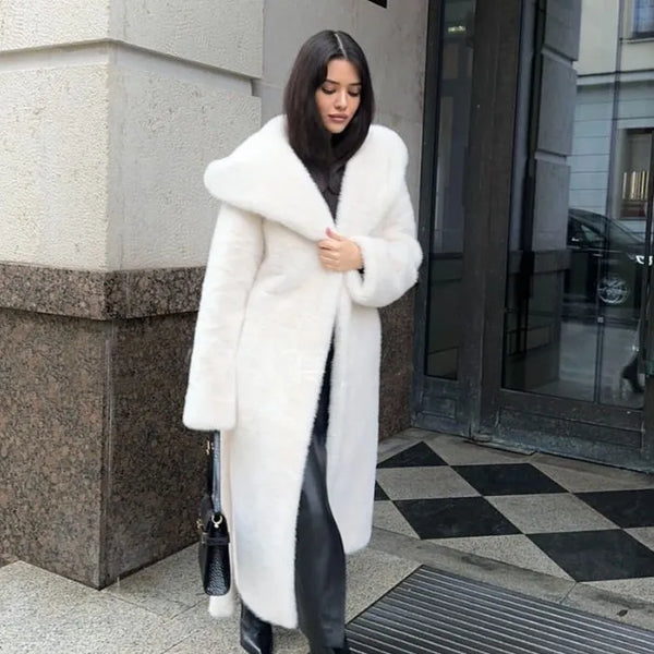 Hooded long plush coat in white styled elegantly with black boots and bag.