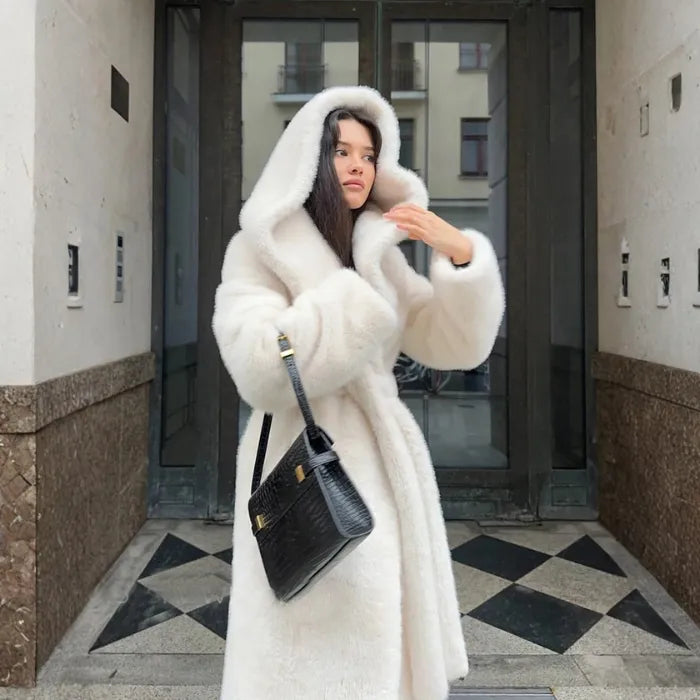 Hooded long plush coat in white paired with black handbag and sleek winter outfit.