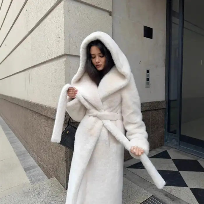 Hooded long plush coat in white with tie belt detail styled for sophisticated and cozy winter wear.