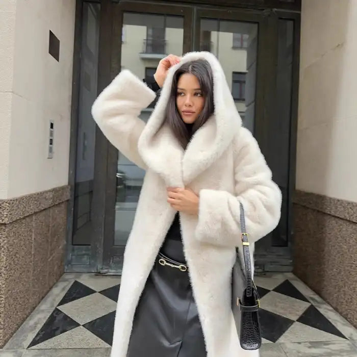 Hooded long plush coat in white styled with black outfit and sleek handbag for modern winter fashion look.