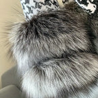 Houndstooth coat with faux fur trim, texture details of gray fur collar and cuffs, laid flat on couch.
