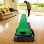 Man using indoor putting green in a living room setting with natural light and couch nearby