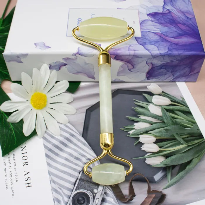 Qingxi Jade Roller on a decorative background with flowers and a box.