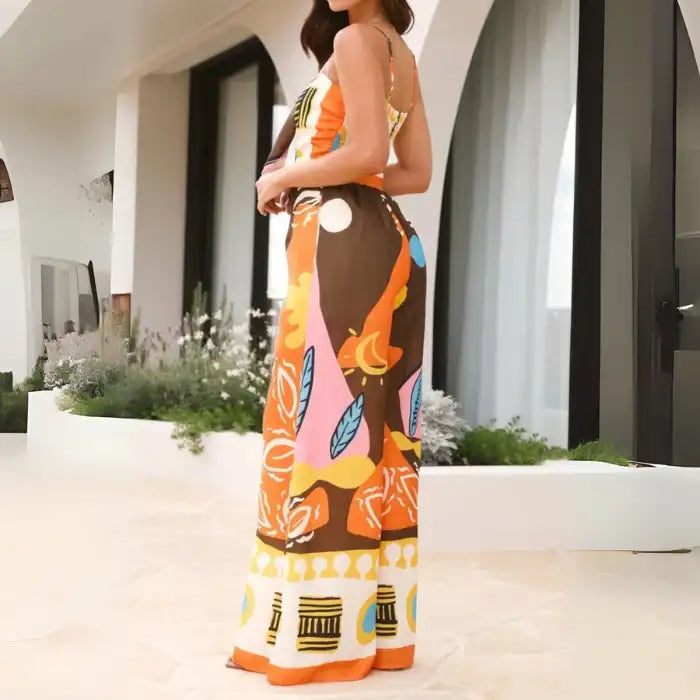  Multicolor jumpsuit with orange, brown, and yellow tropical print styled with strappy back and relaxed fit.