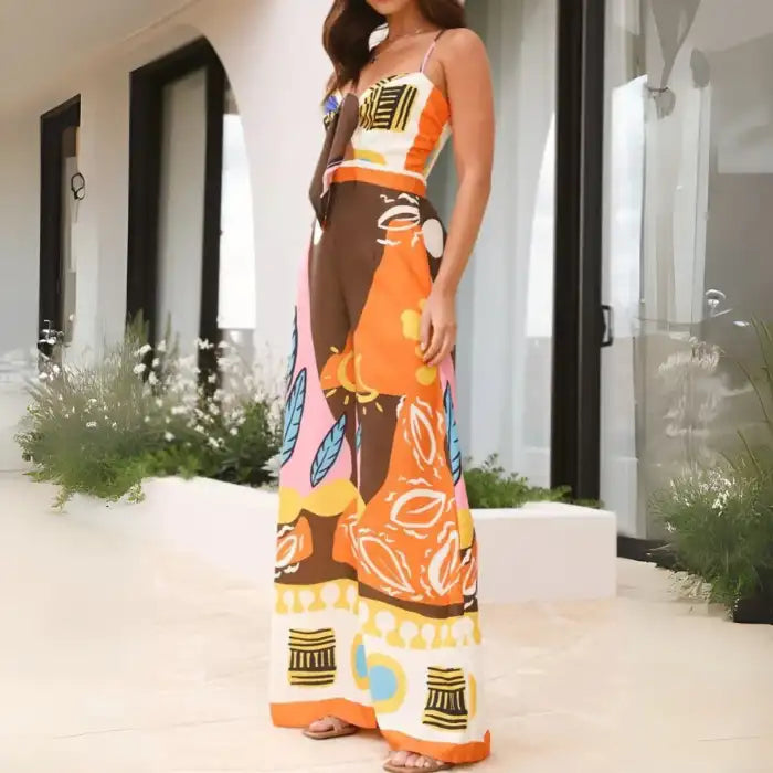 Summer jumpsuit with abstract orange, yellow, and pink print in side profile showing wide legs and tie-front.