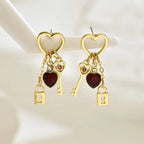 key and locket earrings with gold heart hoops red crystal hearts and dangling lock charms displayed on stand