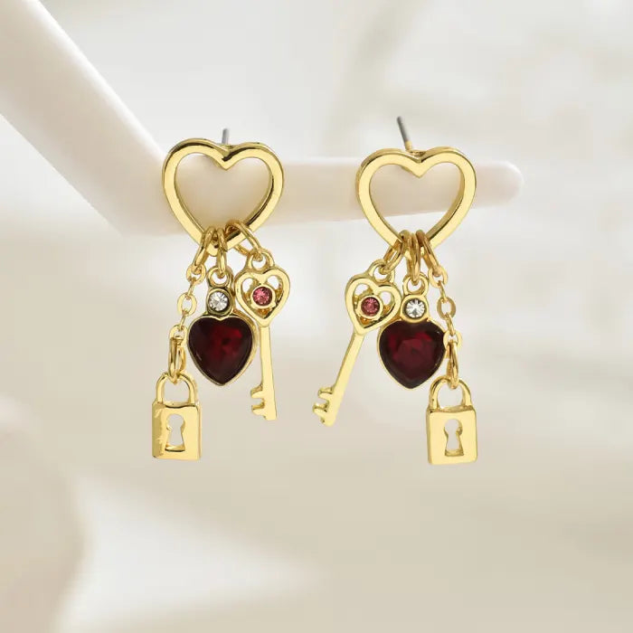 key and locket earrings with gold heart hoops red crystal hearts and dangling lock charms displayed on stand