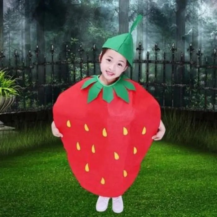 Girl in bright red strawberry kids costume posing outdoors with green grass and forest backdrop.