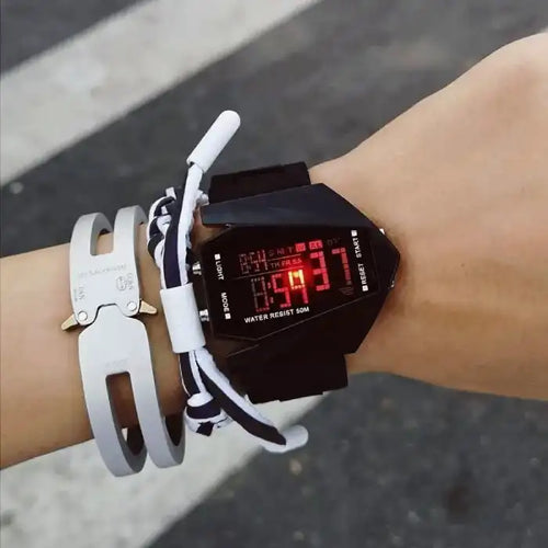 Kids watch with black strap and red LED display, shown on wrist with accessories.