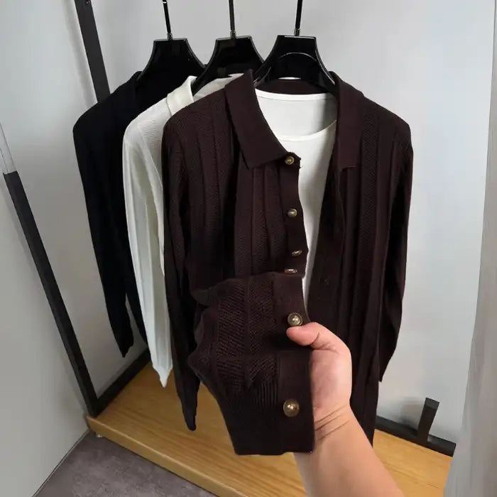  Brown knit cardigan with wooden buttons, held by hand focusing on the sleeve cuff and button detail.