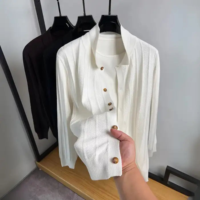 Knit cardigan in white with wooden buttons, held by hand showing button details on sleeve cuff.