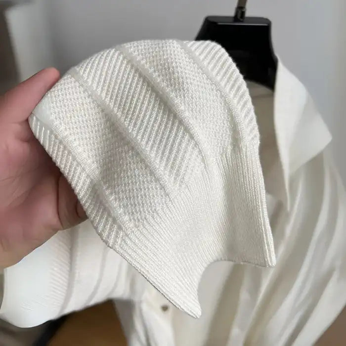 Detailed view of white knit cardigan fabric showing ribbed and textured knit patterns.