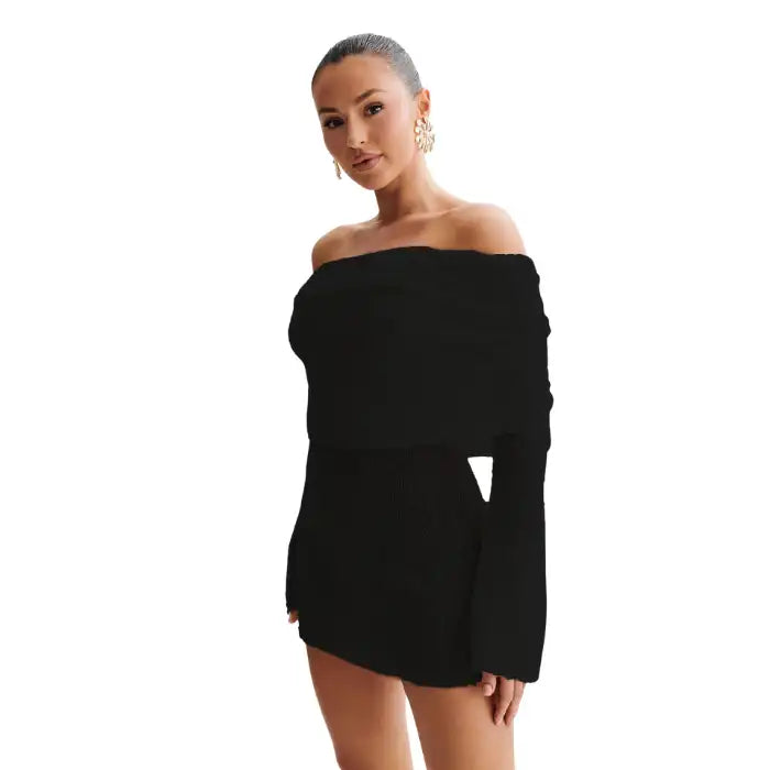 Knitted black dress styled off-shoulder with long sleeves in elegant side-forward model pose.