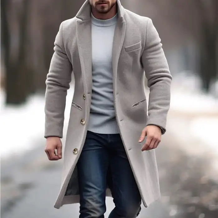 Lapel trench coat in beige worn over sweater and jeans in a stylish snowy winter park setting.