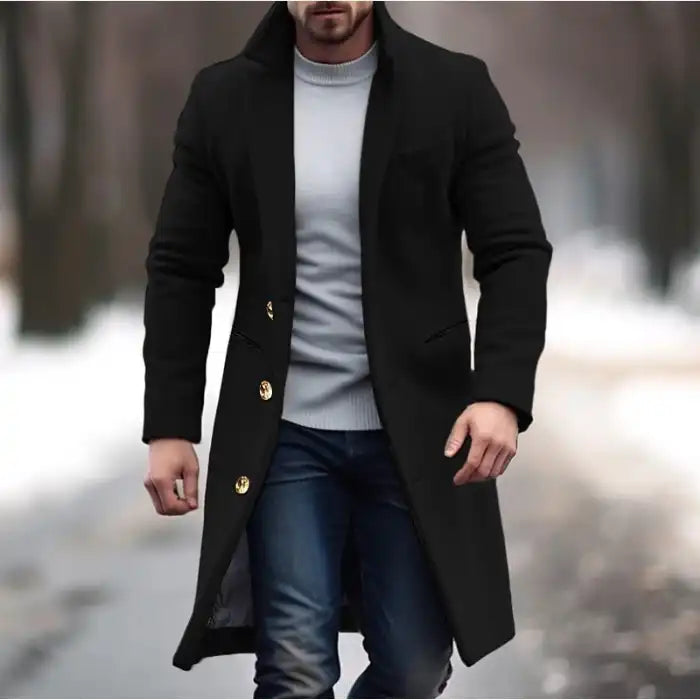 Lapel trench coat in black with gold buttons styled for winter streetwear on a snowy outdoor path.