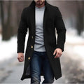 Lapel trench coat in black with gold buttons styled for winter streetwear on a snowy outdoor path.