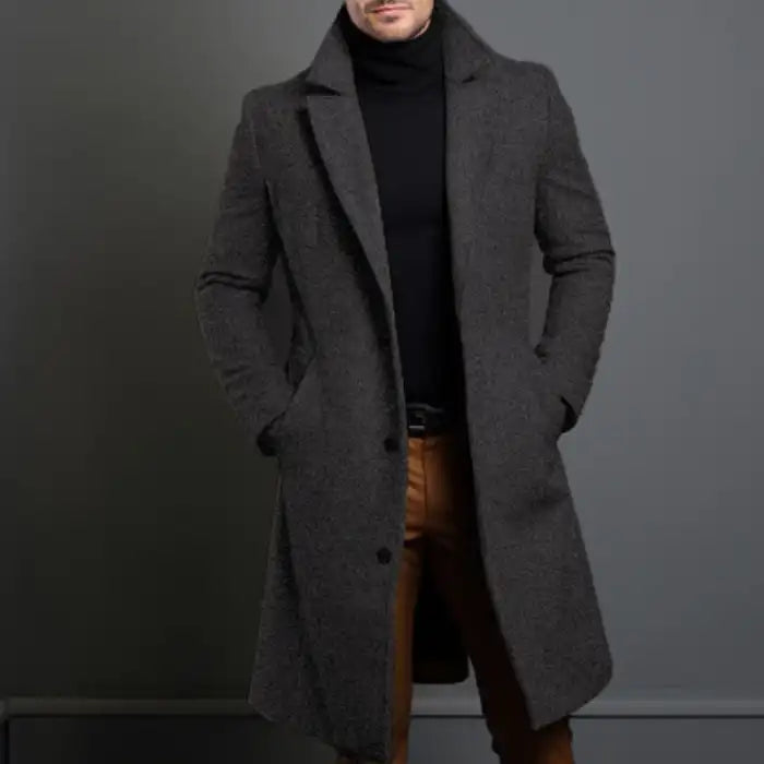 Charcoal lapel trench coat styled with brown pants and black turtleneck for a refined modern look.