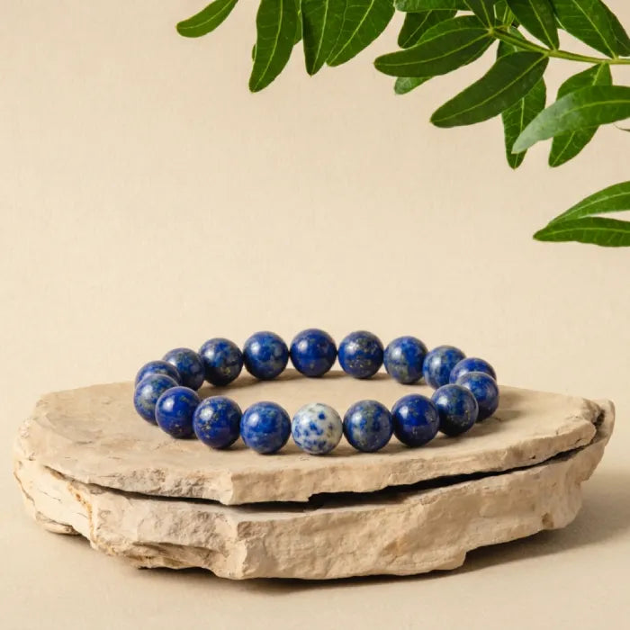 Lapis lazuli bracelet displayed on natural stone with leaf details, polished gemstone jewelry for earthy luxury