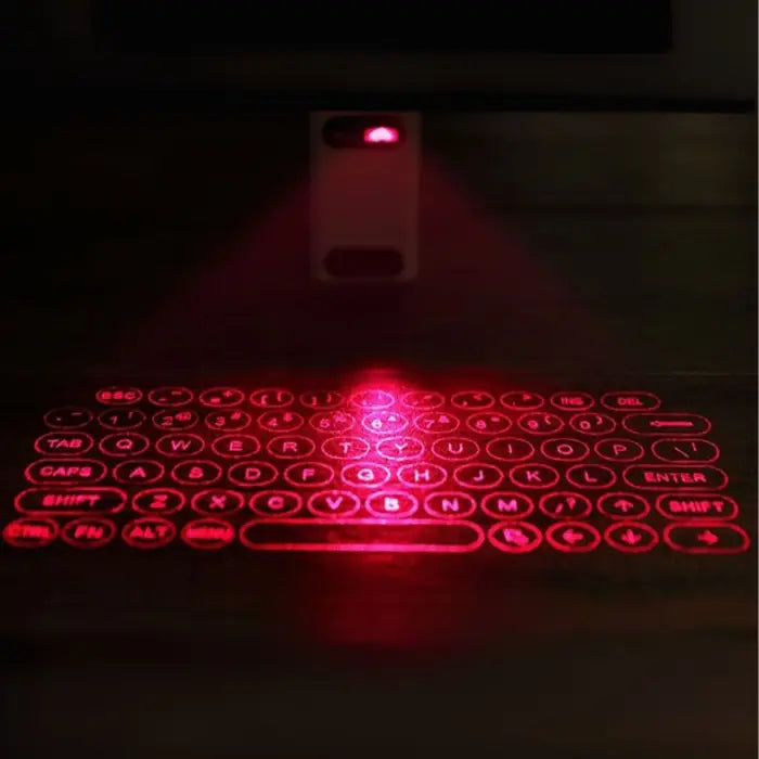 Red laser keyboard projected onto a dark surface with a remote control.