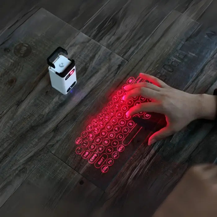 Laser projection keyboard showing red virtual keyboard with hand typing on wood surface.