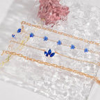 Layered gold bracelets with blue gemstone details, including floral and butterfly-inspired designs.