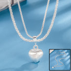 layered silver heart necklace with double chains and brushed silver heart pendant displayed on blue background