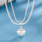 layered silver heart necklace with shiny double chains and brushed silver heart pendant shown in front display
