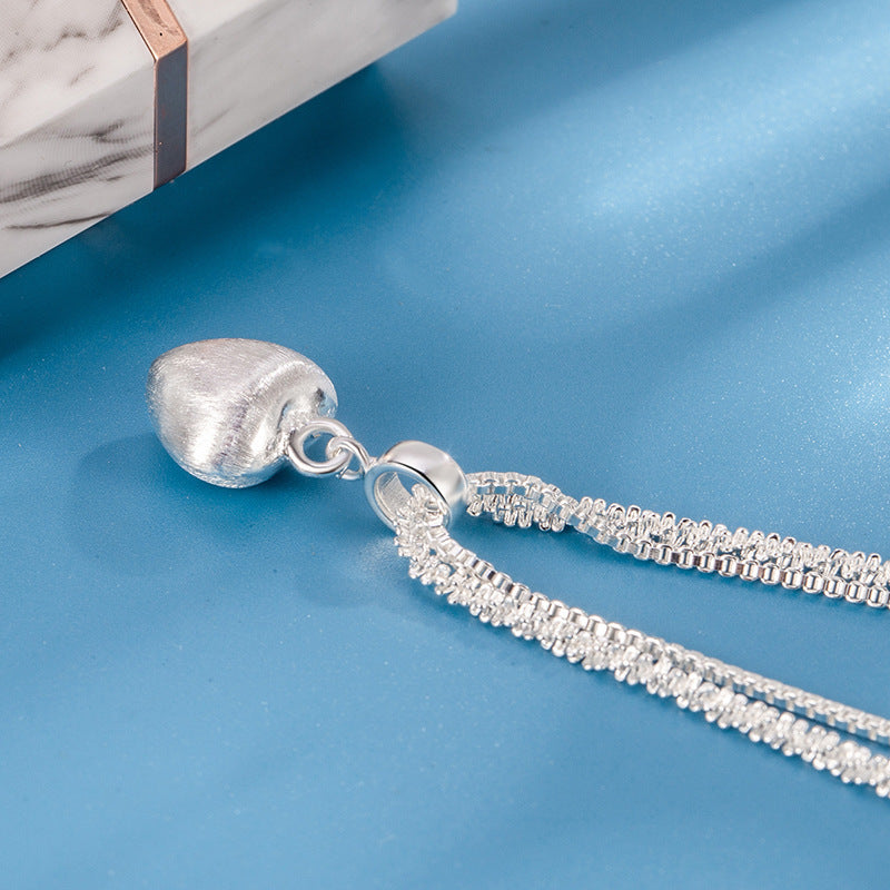 layered silver heart necklace shown from side angle featuring brushed heart pendant and double chain detail