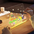 LED acrylic drawing board showing a user drawing a Merry Christmas scene with glowing lights, offering a fun hands-on creative activity.