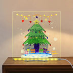 LED acrylic drawing board glowing with a colorful Christmas tree and presents, creating a festive light-up holiday art display at home.