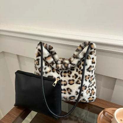 White leopard print faux fur handbag paired with a black zippered pouch on a glass table.