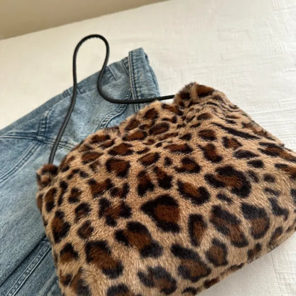 Leopard print faux fur shoulder bag with black straps displayed on top of a denim jacket.