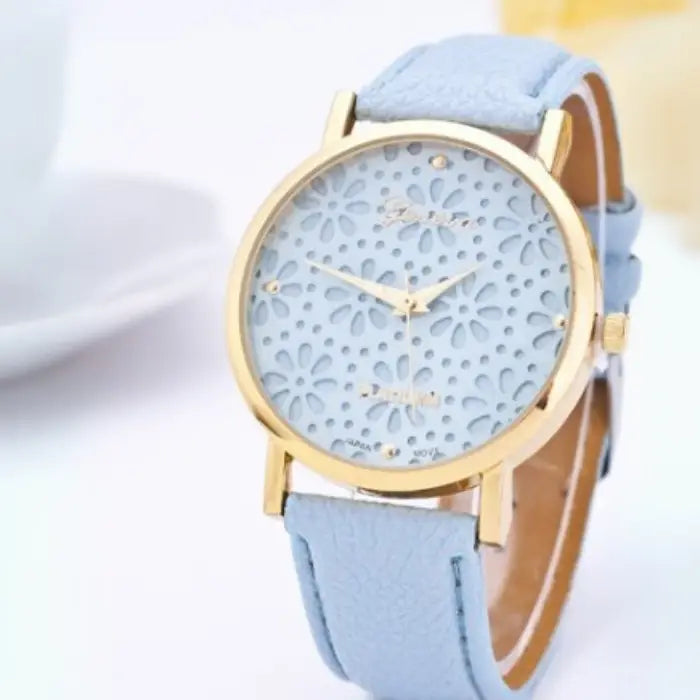 Light blue women's watch with a gold floral-patterned dial and light blue leather strap.