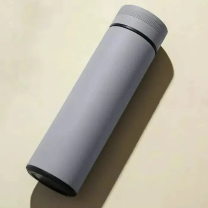 Light gray vacuum insulated bottle with ribbed lid on cream background, casting shadow