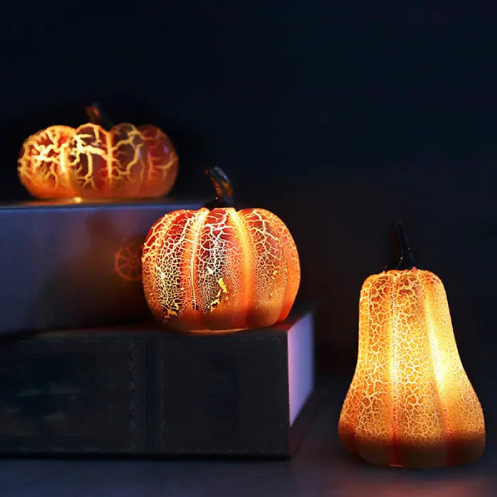 Light up pumpkin decorations glowing brightly in dark room on books for cozy seasonal ambiance