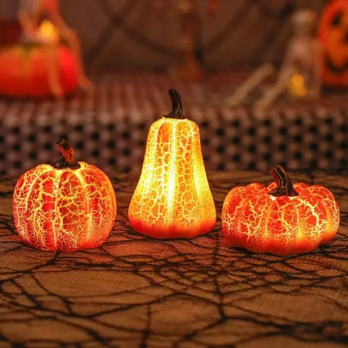 Light up pumpkin decorations glowing brightly on Halloween-themed table with webbed cloth