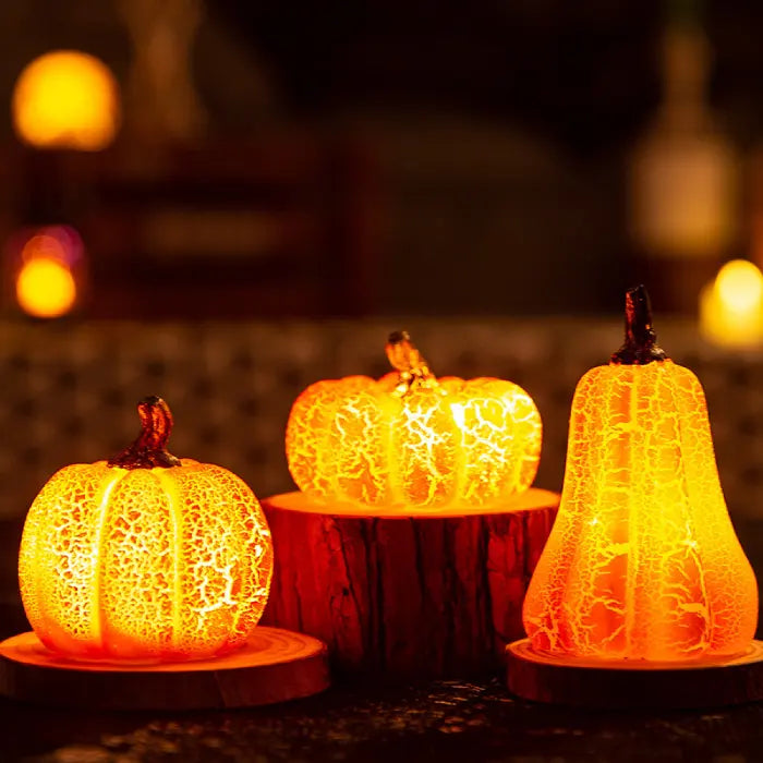 Light up pumpkin decorations glowing warmly on rustic wood stands with autumn ambiance